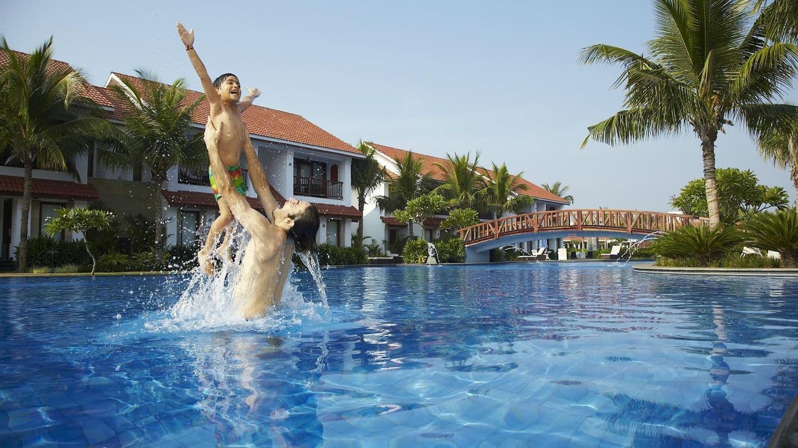 Landscaped swimming pool with a footbridge and resort blocks at Radisson Blu Resort Temple Bay, Mamallapuram