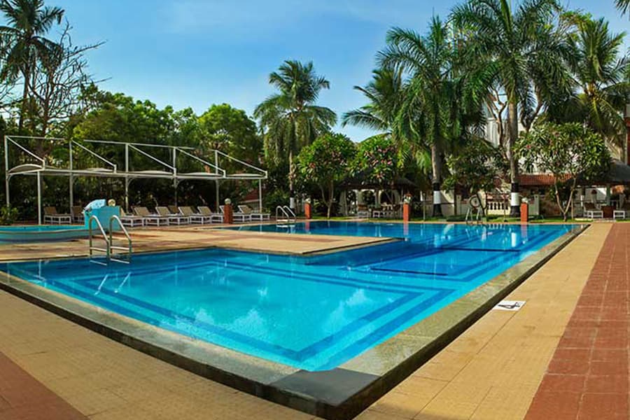 Swimming pool bordered by coconut palms at Ideal Beach Resort, Mamallapuram