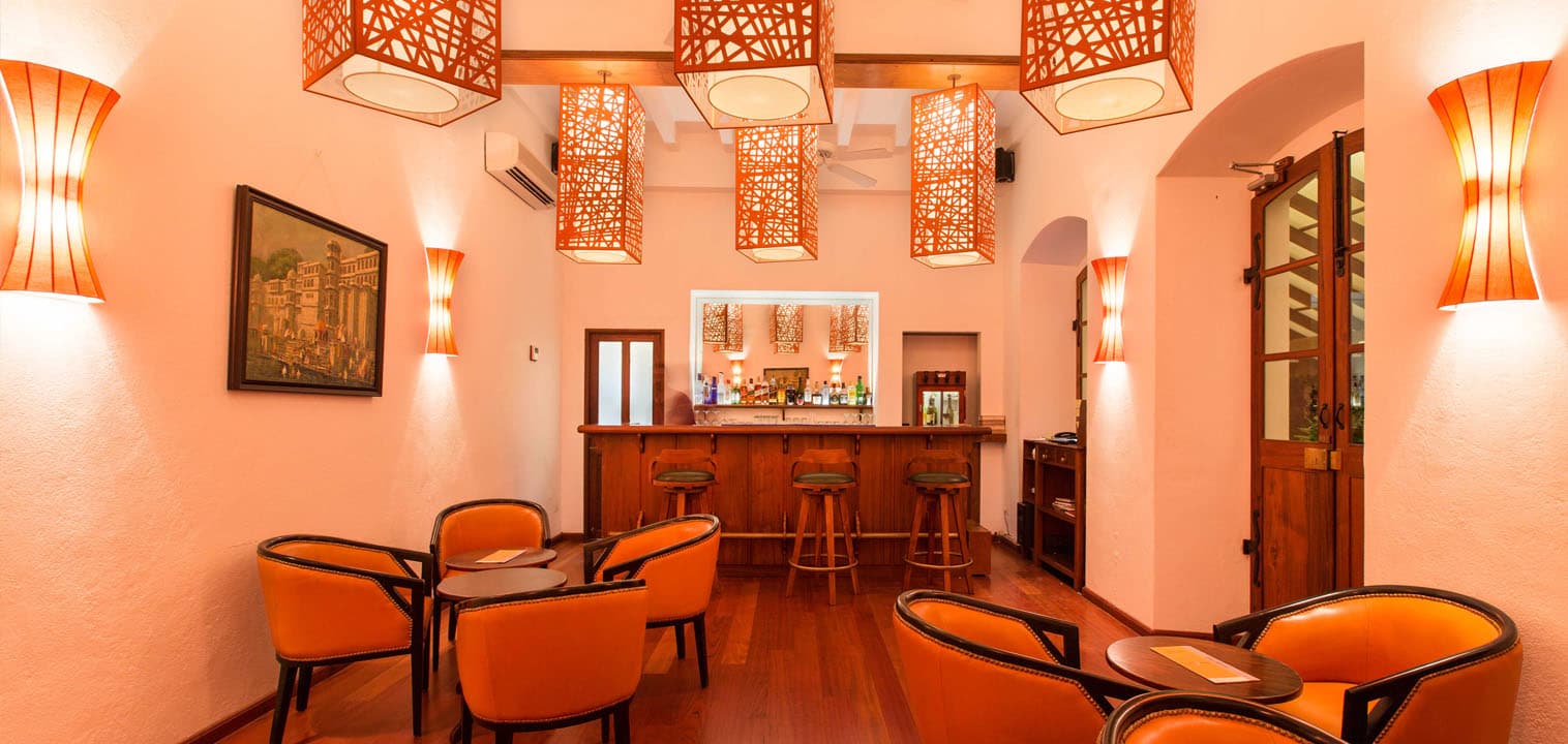 Cocktail bar with orange walls and carved screens at Palais de Mahe, Puducherry