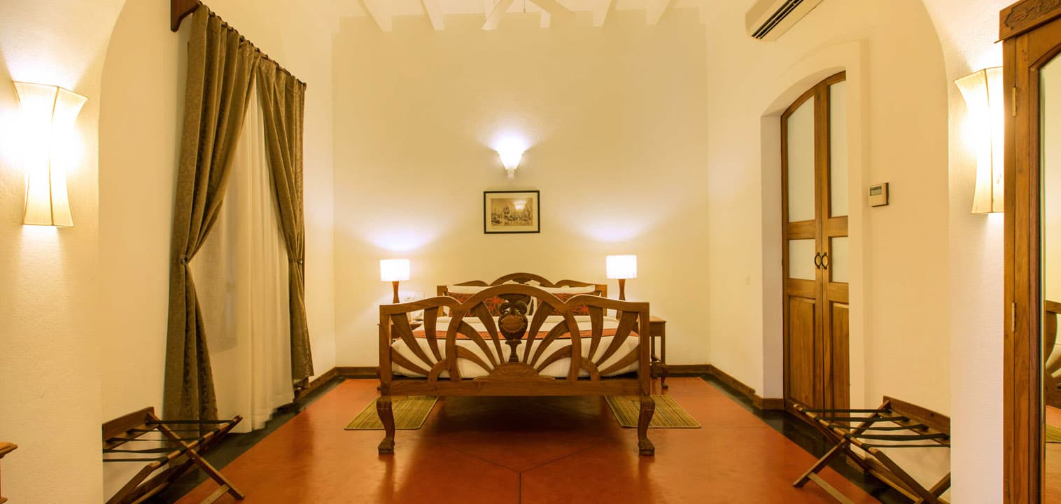 Superior room with a four-poster bed and antique furniture at Palais de Mahe, Puducherry
