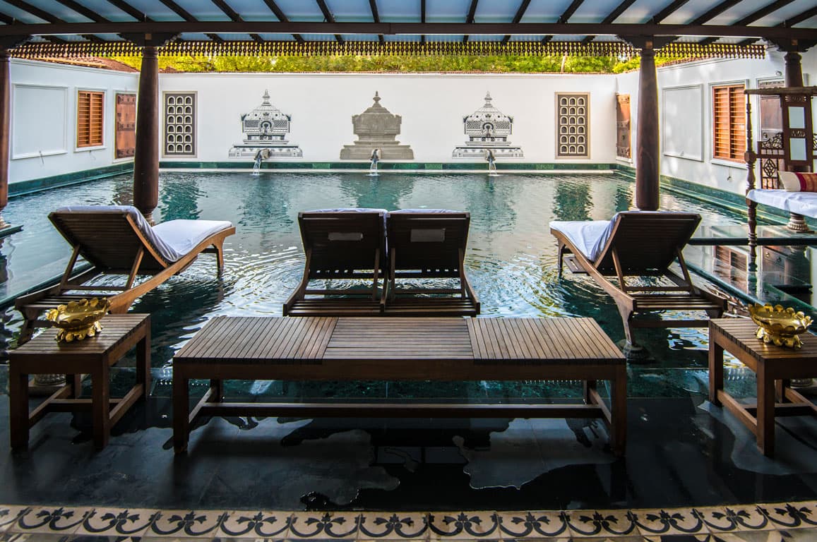 Poolside timber sun loungers facing a fountain wall in the courtyard at Svatma, Thanjavur