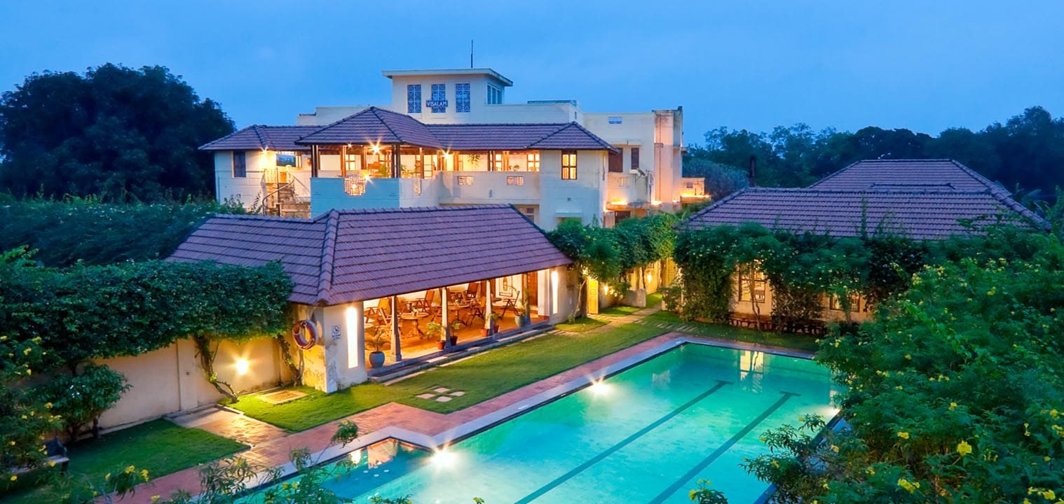 Outdoor swimming pool with the Chettinad mansion behind it at Visalam, a CGH Earth hotel, Kanadukathan