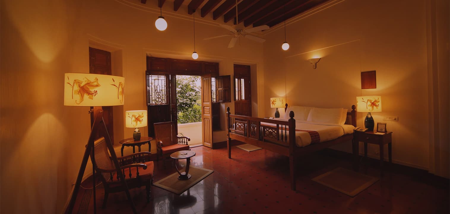 Chettinad Room with wooden furniture, seating area and a polished red-oxide floor at Visalam, a CGH Earth hotel