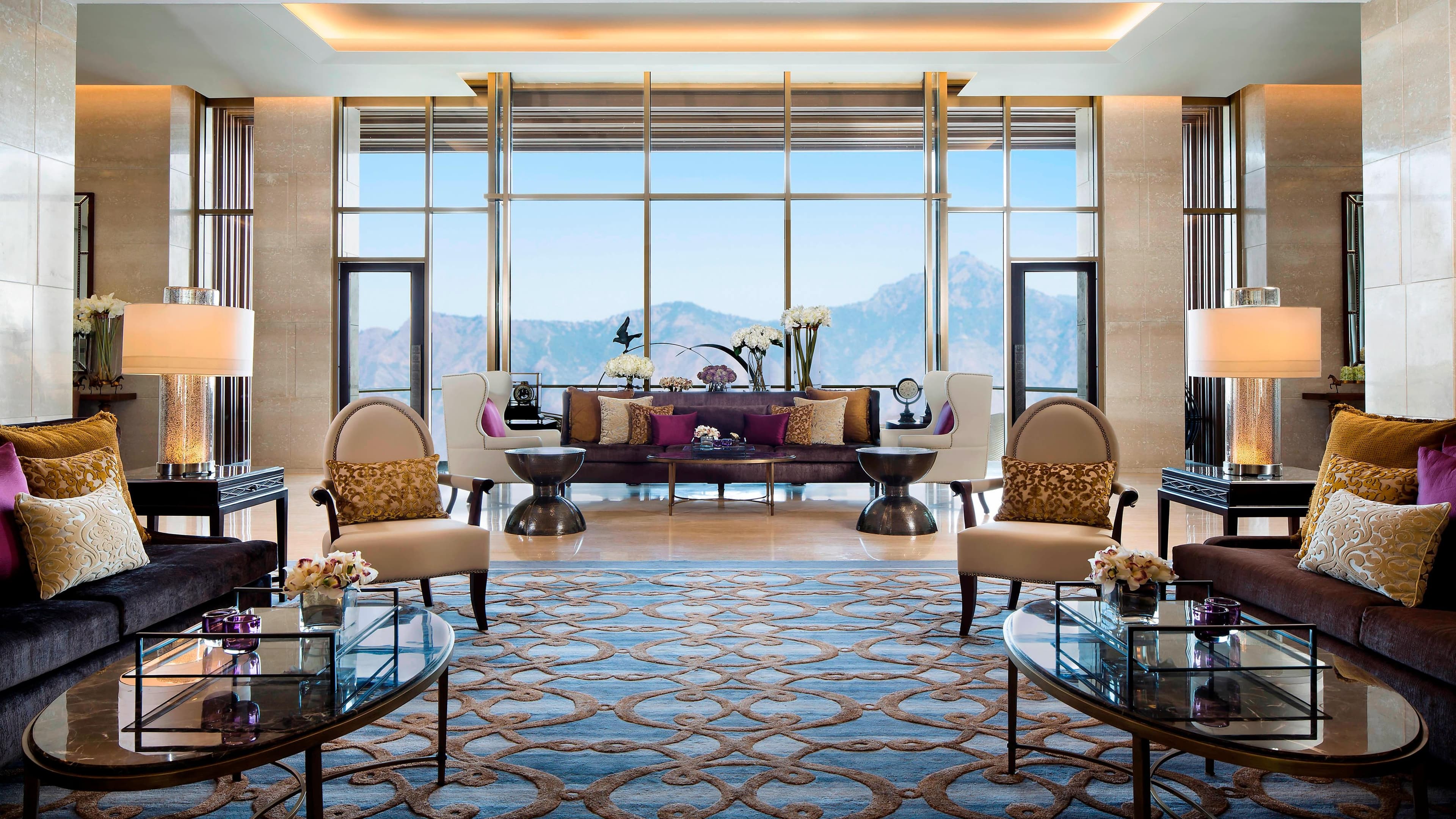 Lobby lounge seating area with floor-to-ceiling windows overlooking the Himalayas at JW Marriott Mussoorie Walnut Grove Resort & Spa.
