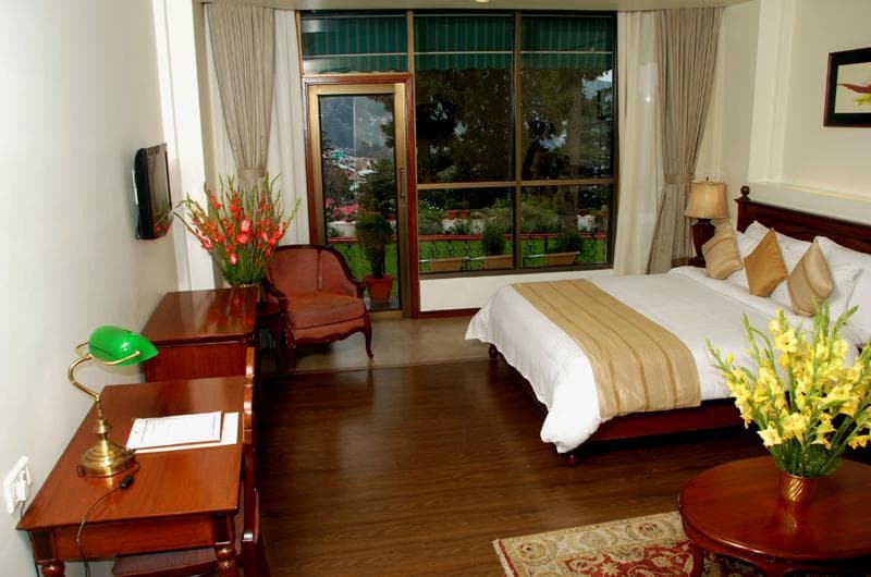 Manu Maharani Nainital Club Room with king bed, wooden furniture, and balcony overlooking the garden