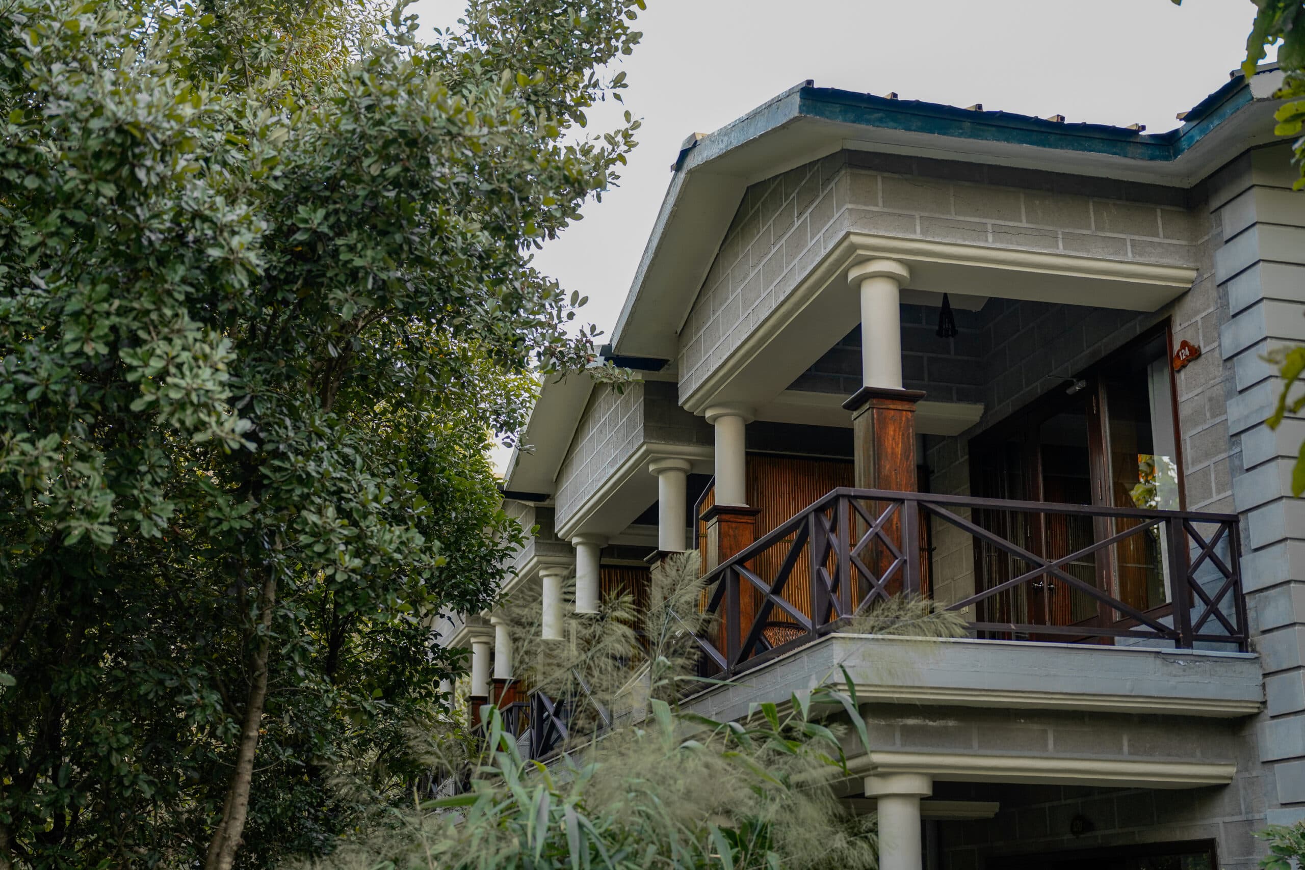 Aahana - The Corbett Wilderness stone-and-timber cottage exterior with covered balconies, viewed from below through trees