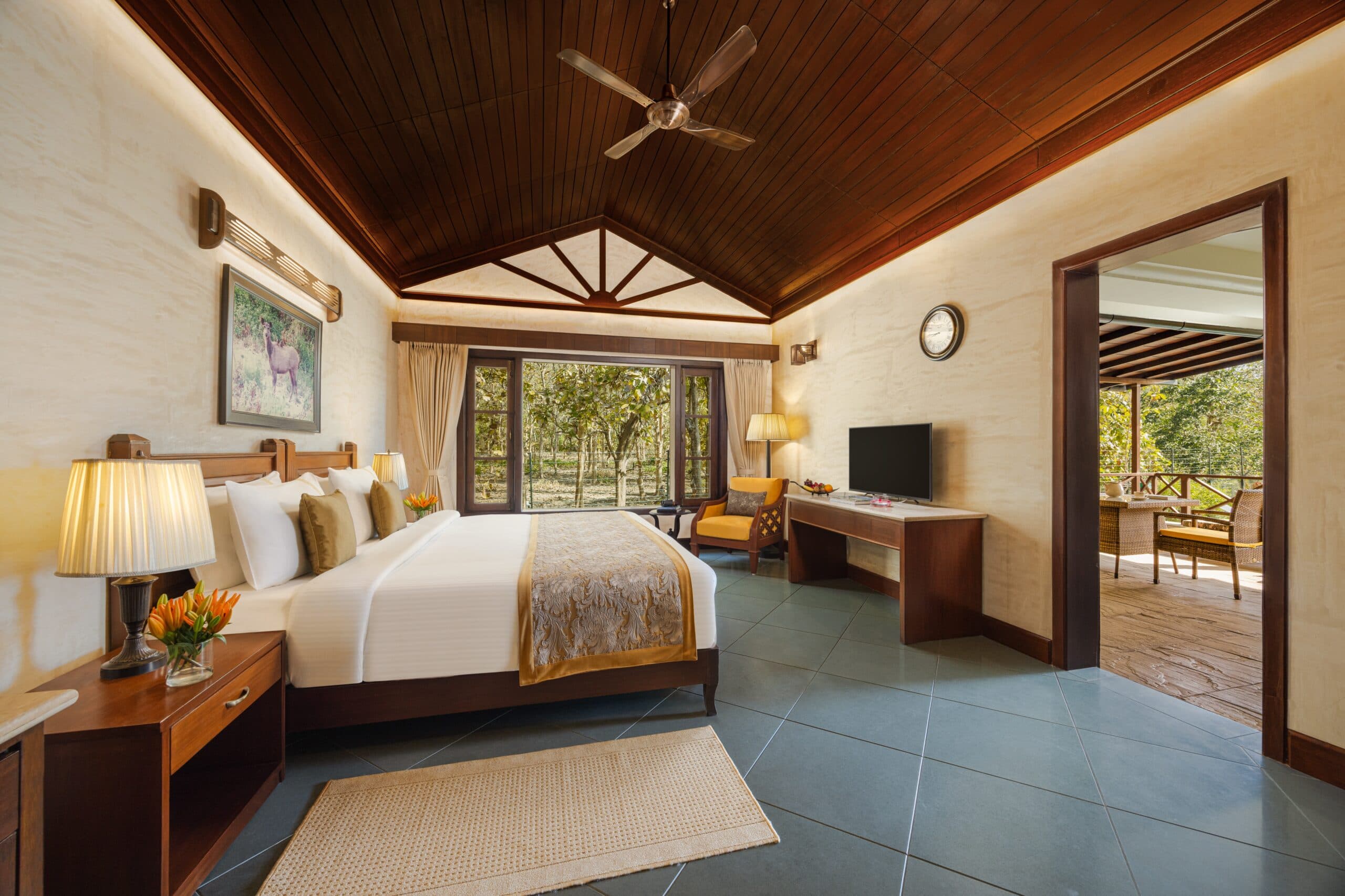 Aahana - The Corbett Wilderness forest villa bedroom with four-poster bed, wildlife artwork, and a private deck opening to trees