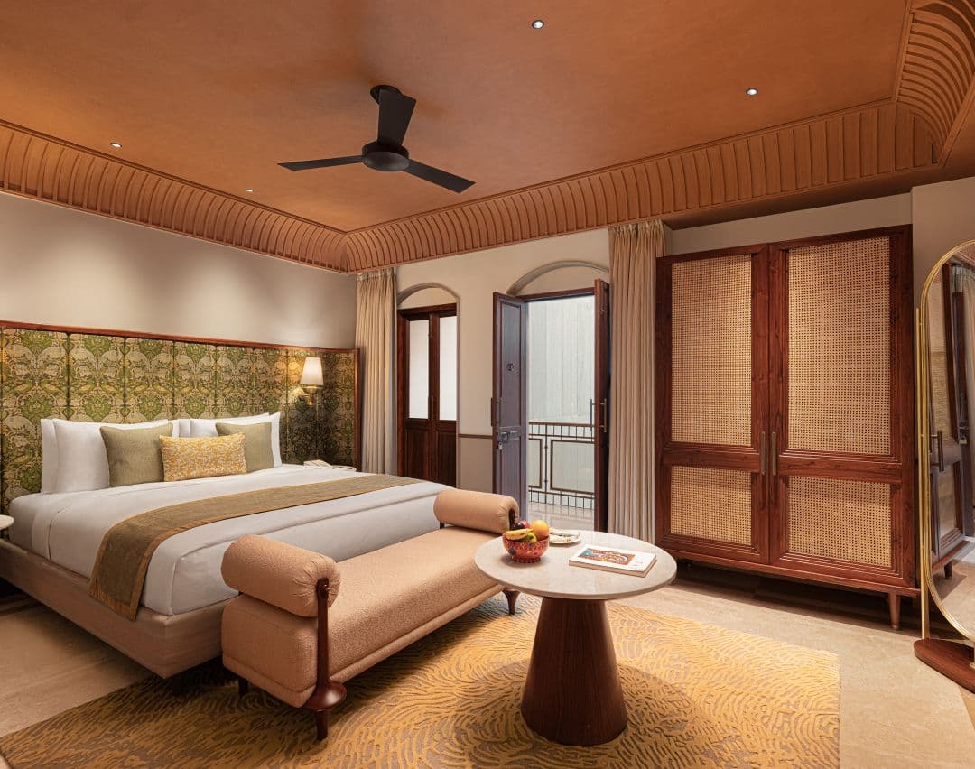 Haveli Hari Ganga higher-category room with king bed, tall arched mirror, wardrobe, and a daybed at the foot of the bed