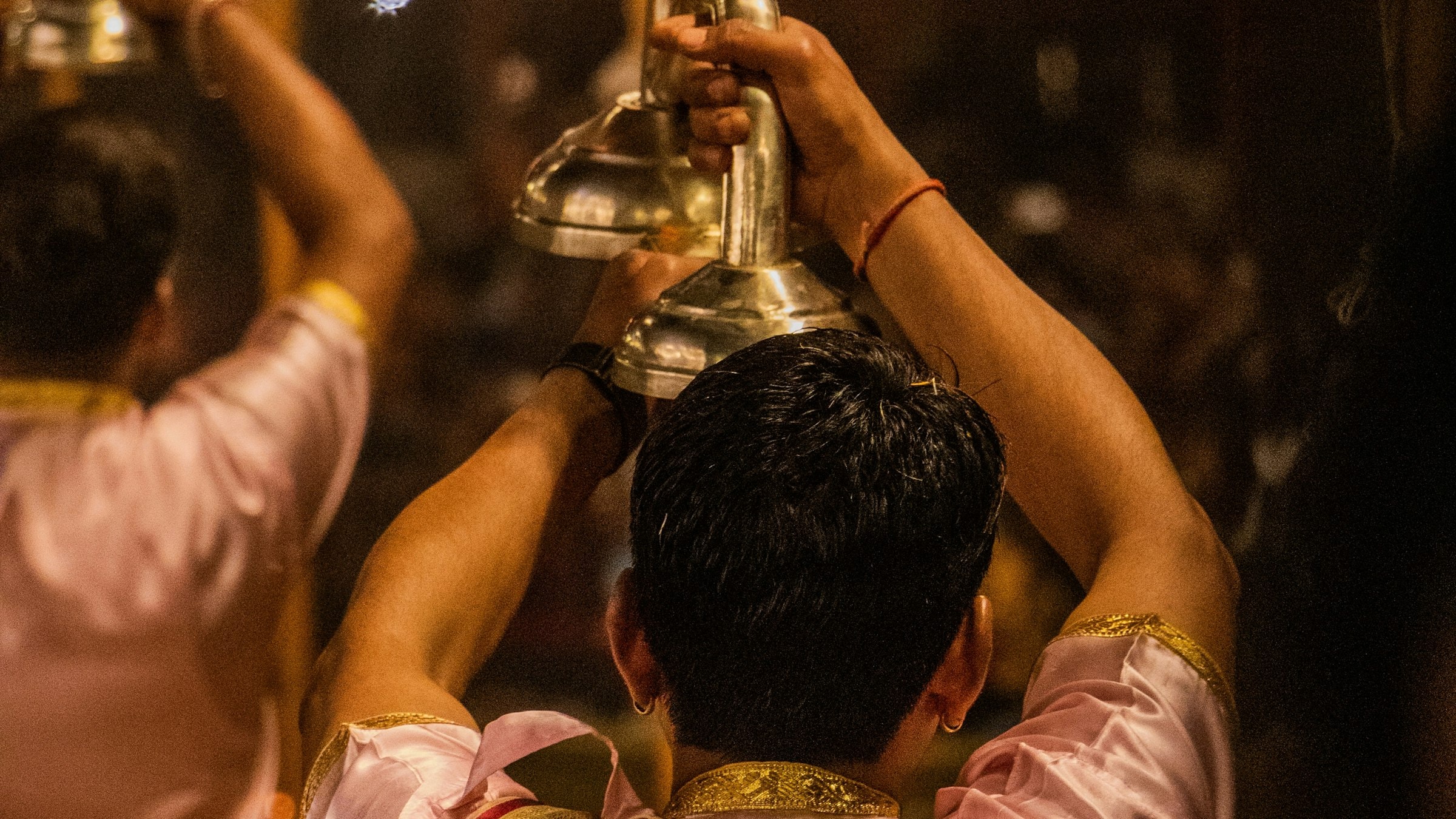 Priests perform the evening Ganga Aarti fire ritual with tiered lamps at dusk on the riverbank.