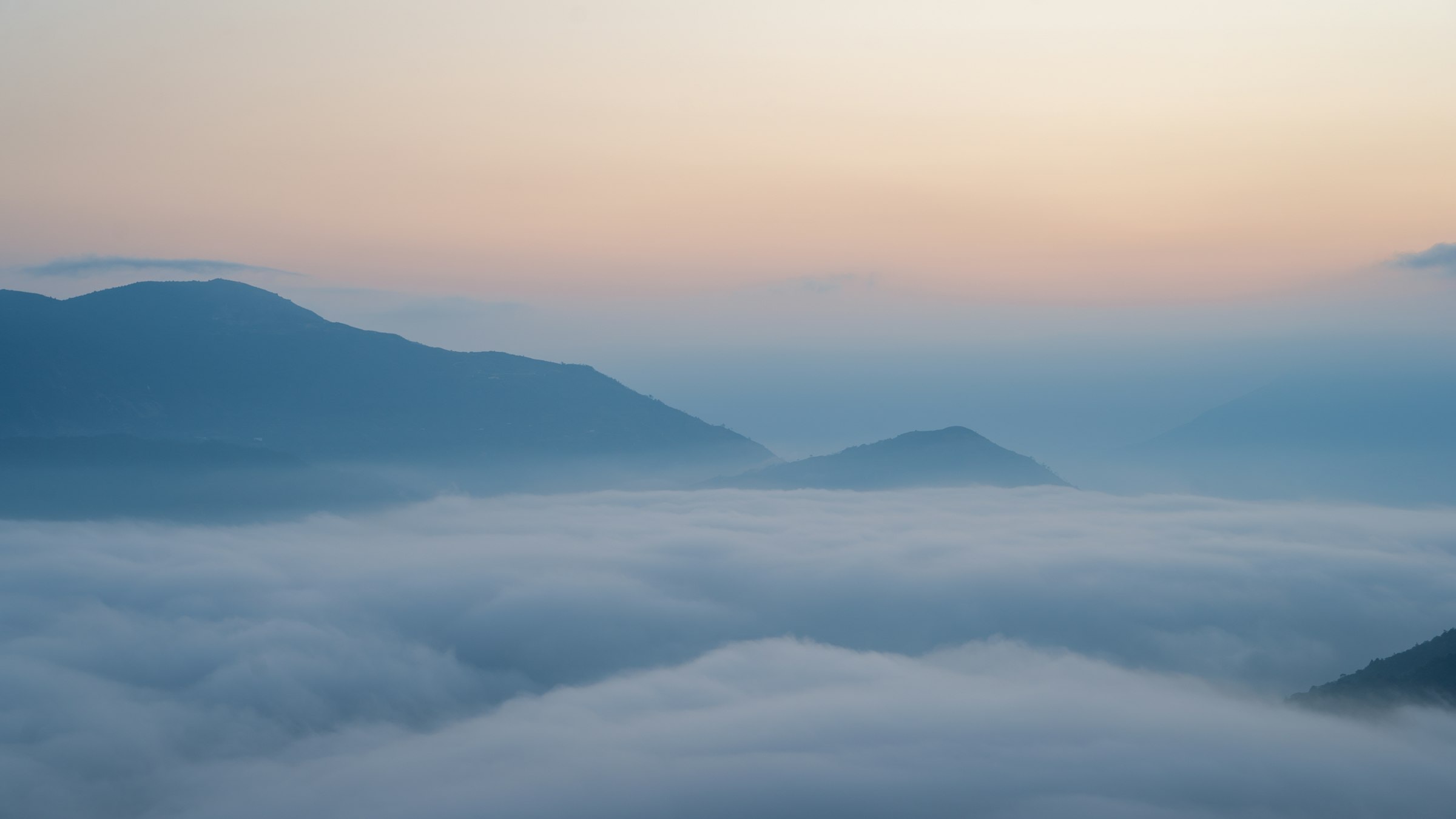 Himalayan peaks rise above a sea of clouds at dawn.