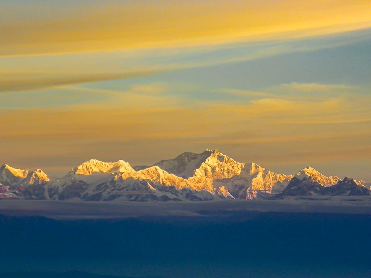 Snow-capped Kanchenjunga peaks glowing gold at sunrise, viewed from Tiger Hill near Darjeeling