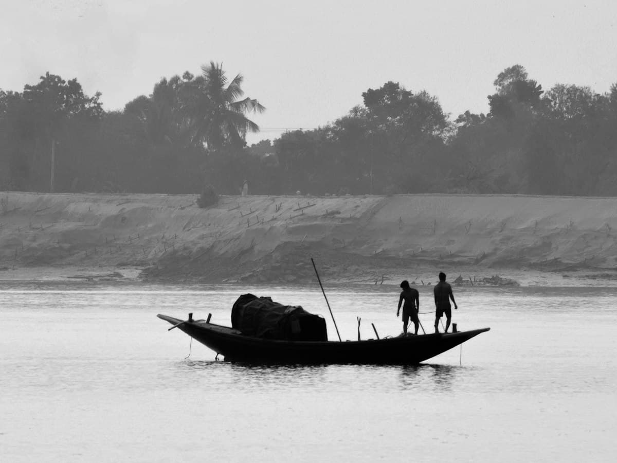 A wooden boat with two people on a Sundarbans waterway, West Bengal
