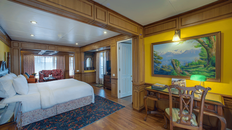 Wood-panelled suite at MAYFAIR Hill Resort Darjeeling with a king bed, sofa seating area, and a writing desk