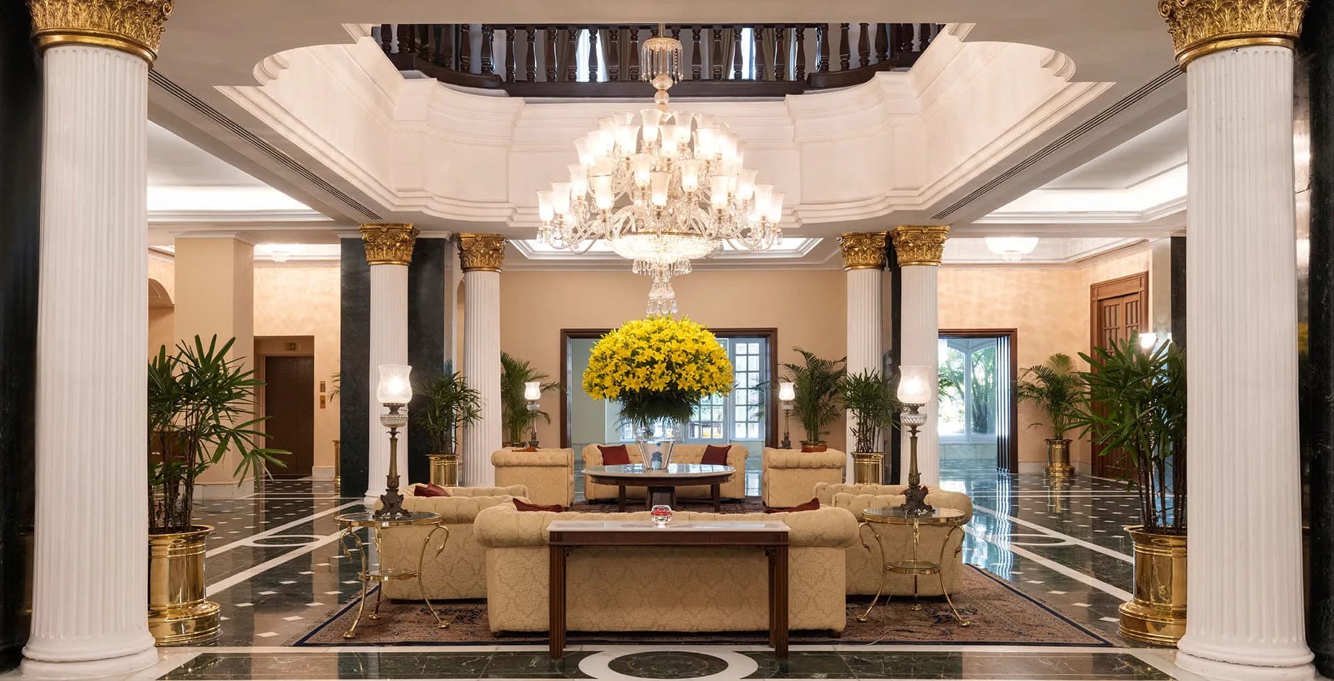 Marble lobby of The Oberoi Grand, Kolkata, with white Corinthian columns, a crystal chandelier, and a double-height atrium