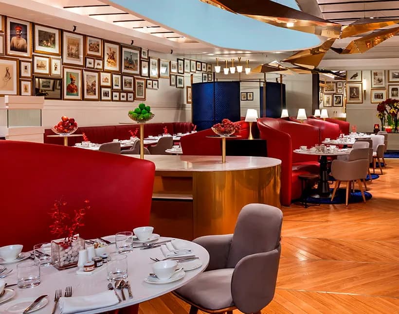 threesixtythree restaurant at The Oberoi Grand, Kolkata, with red booth seating, gallery-hung wall art, and a sculptural gold ceiling feature