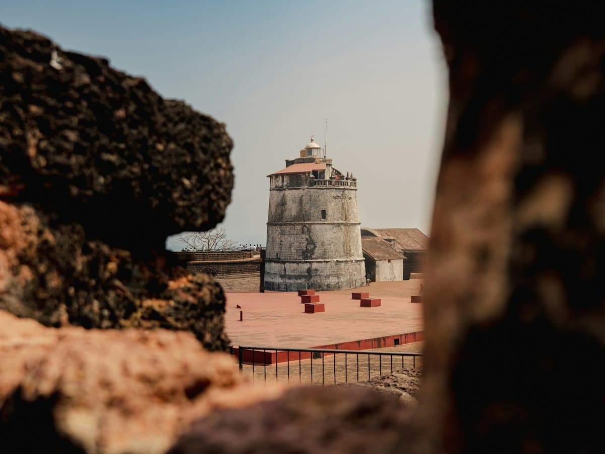 Fort Aguada's old stone lighthouse framed by rocks, Candolim