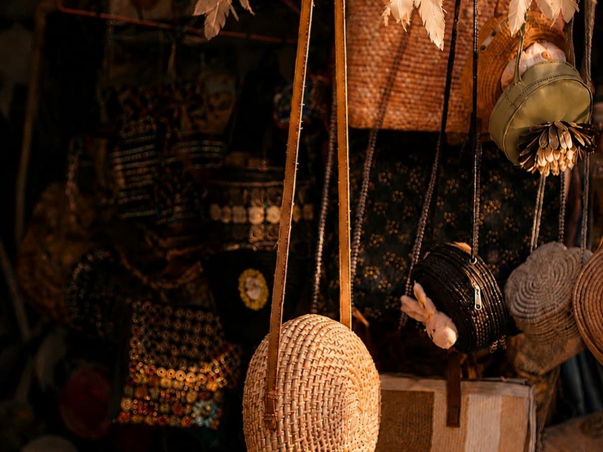 Woven straw bags and dream catchers hanging at a bohemian market stall in Anjuna, Goa