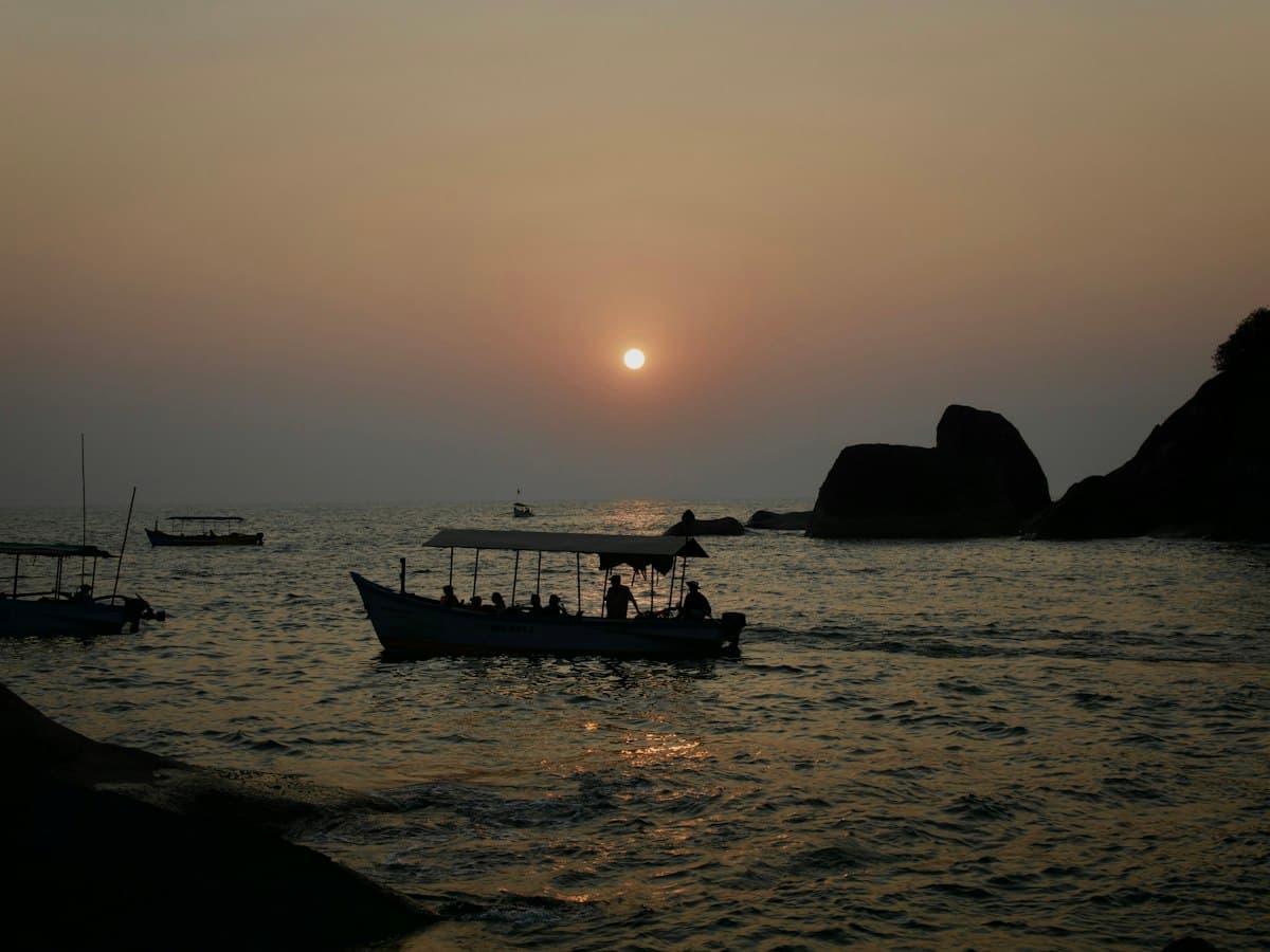 Boats cruising at sunset off Butterfly Beach, South Goa