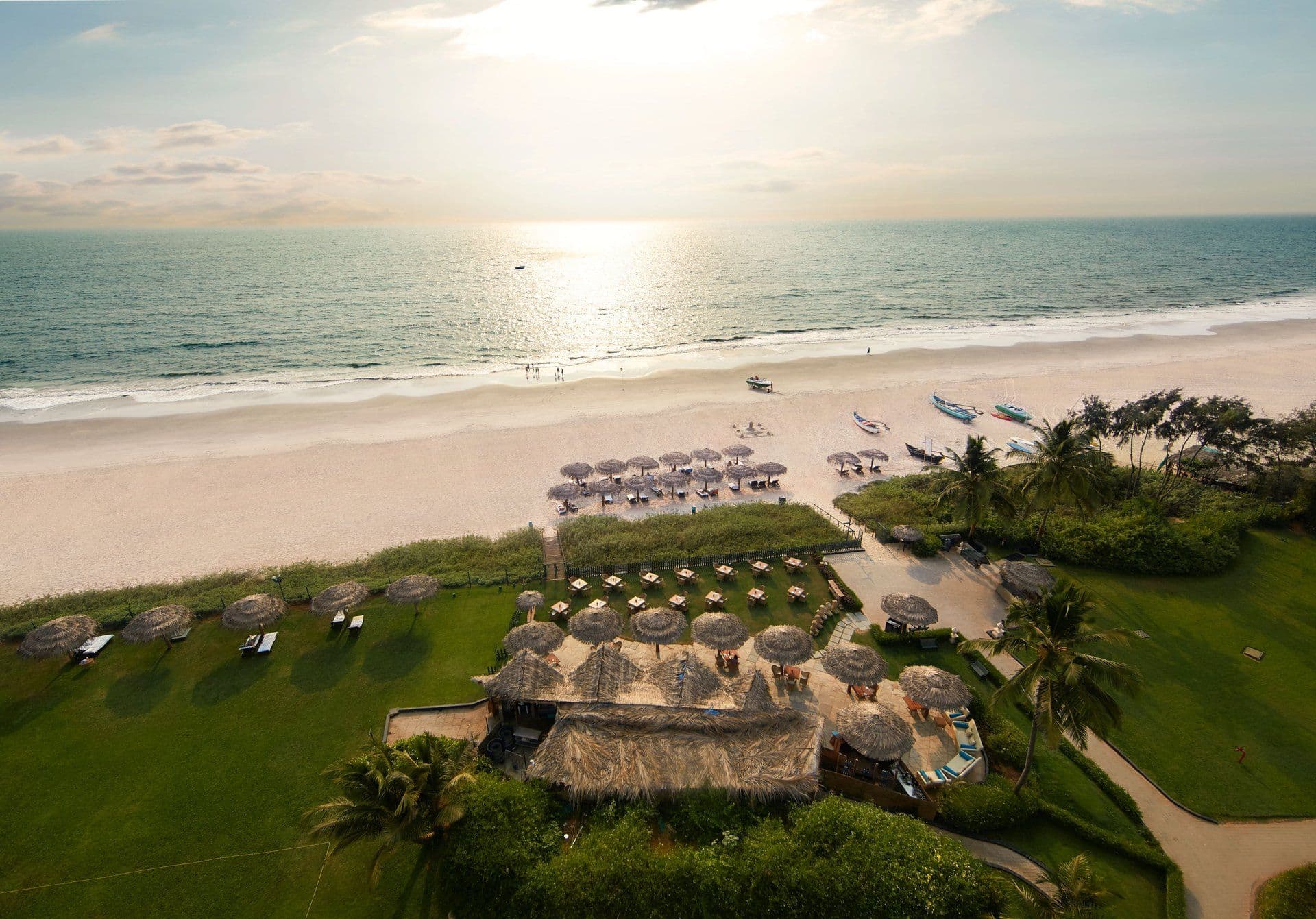Sunrise over the white-sand beach and beach hut at Taj Exotica Resort & Spa, Goa
