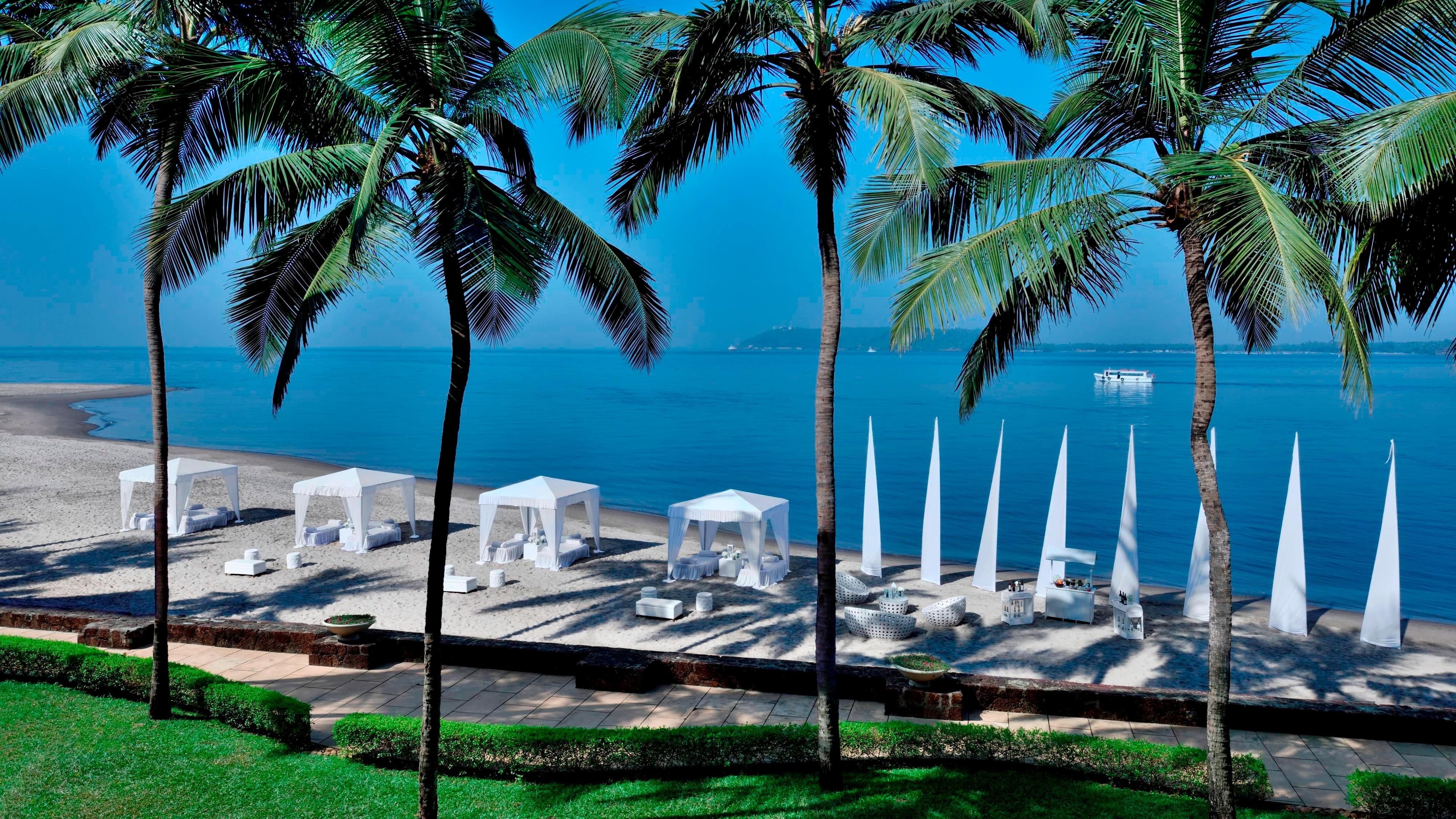 Beachfront cabanas framed by coconut palms at Goa Marriott Resort & Spa, Miramar