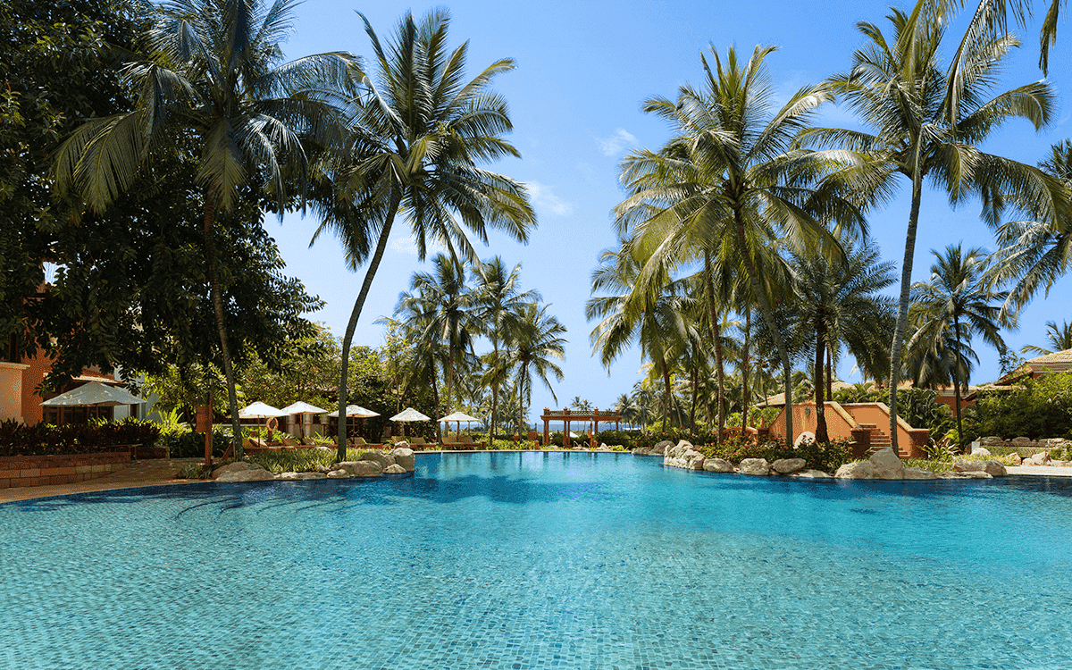 Swimming pool fringed by coconut palms at ITC Grand Goa Resort & Spa