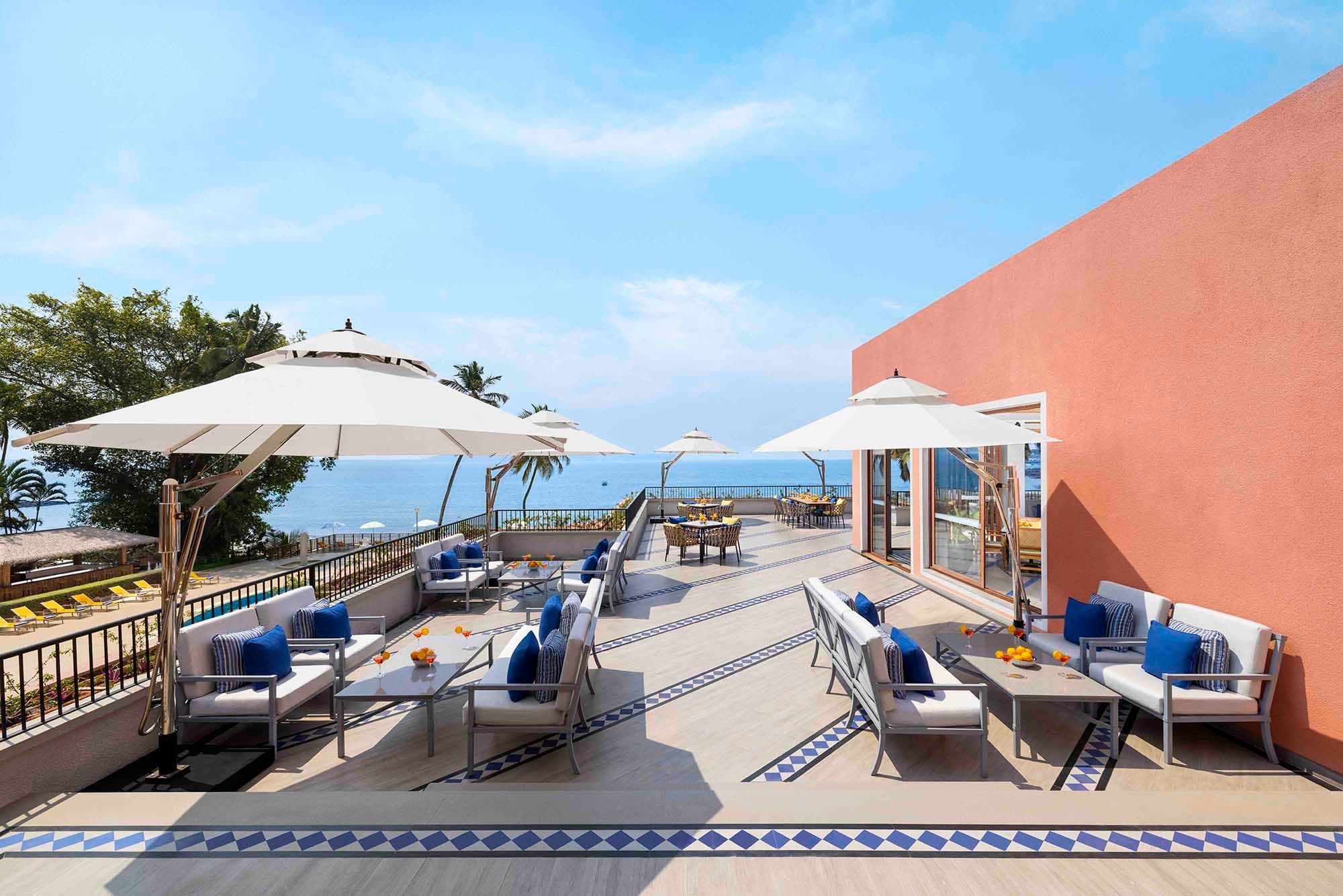 Sea-view terrace with umbrellas and cushioned seating at Taj Cidade de Goa Heritage