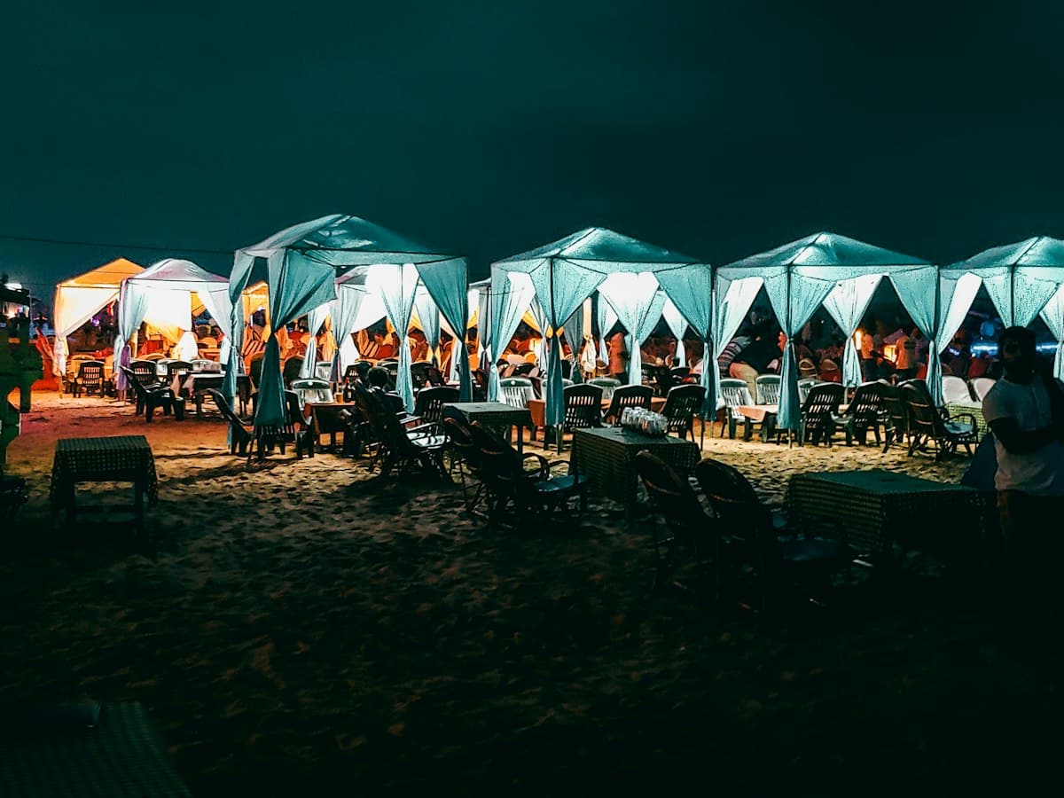 Evening crowd at lit-up beach-side tables in Goa