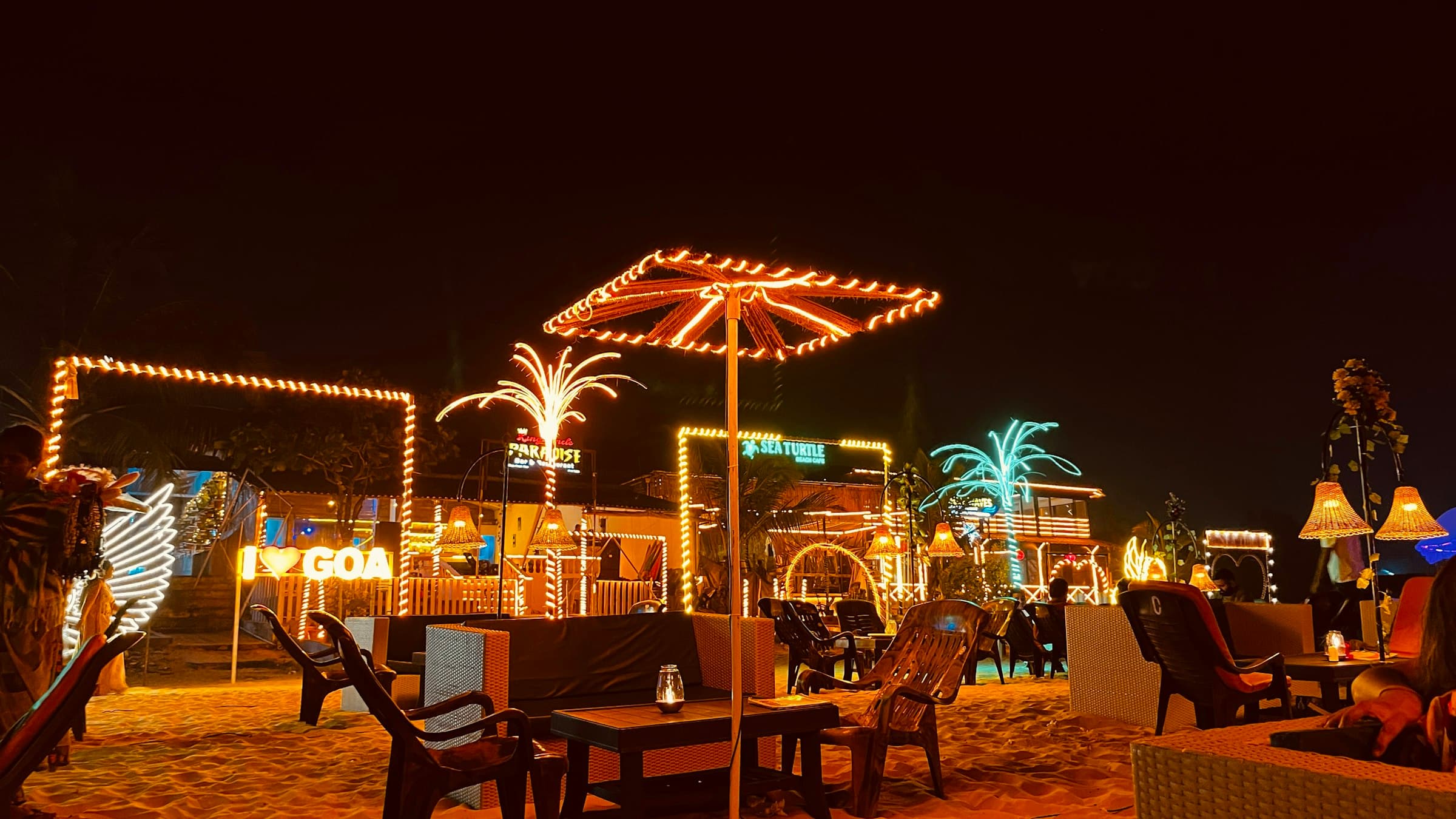 Night-time beach tables and string lights on a Goa beach