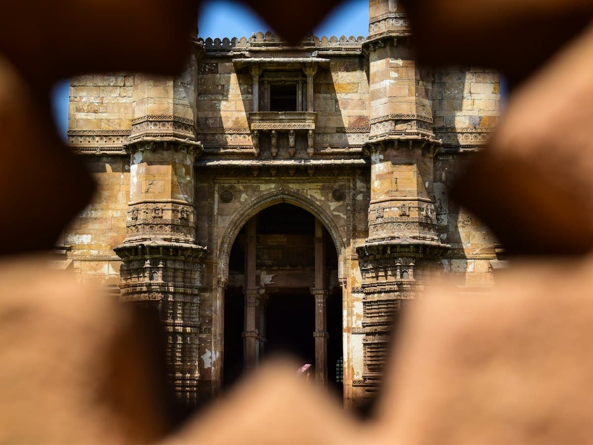 Carved stone facade of Jama Masjid, Ahmedabad, glimpsed through a star-shaped lattice opening