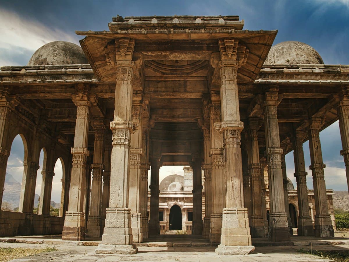 Carved stone pillared pavilion of the Champaner monuments with a domed mosque beyond, Gujarat