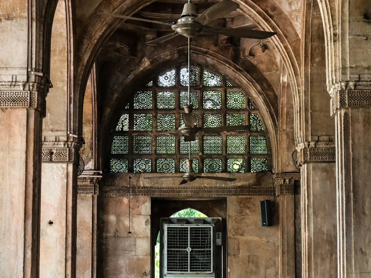 Carved stone jali window framed by arches inside the Sidi Saiyyed Mosque in Ahmedabad, Gujarat.
