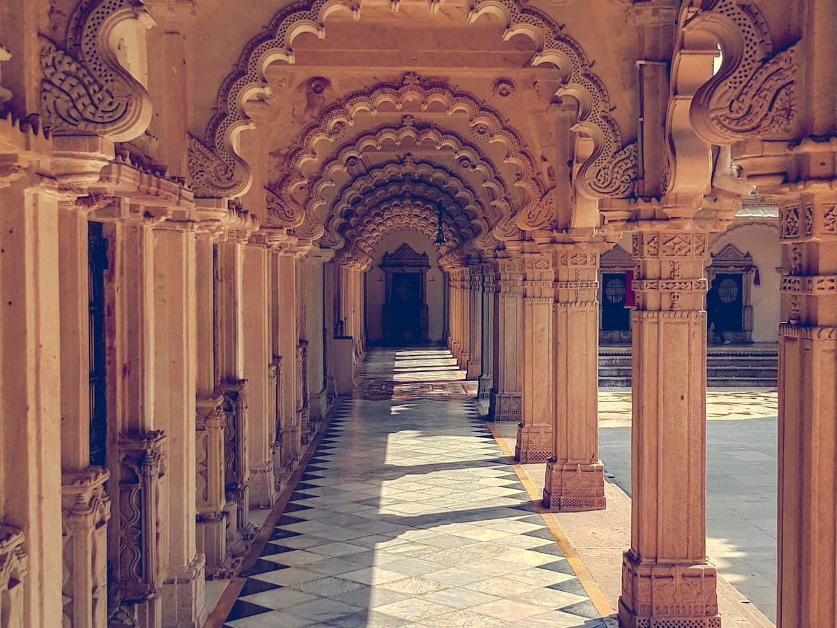 Carved sandstone arched cloister with chequered marble floor at the Hutheesing Jain Temple, Ahmedabad.