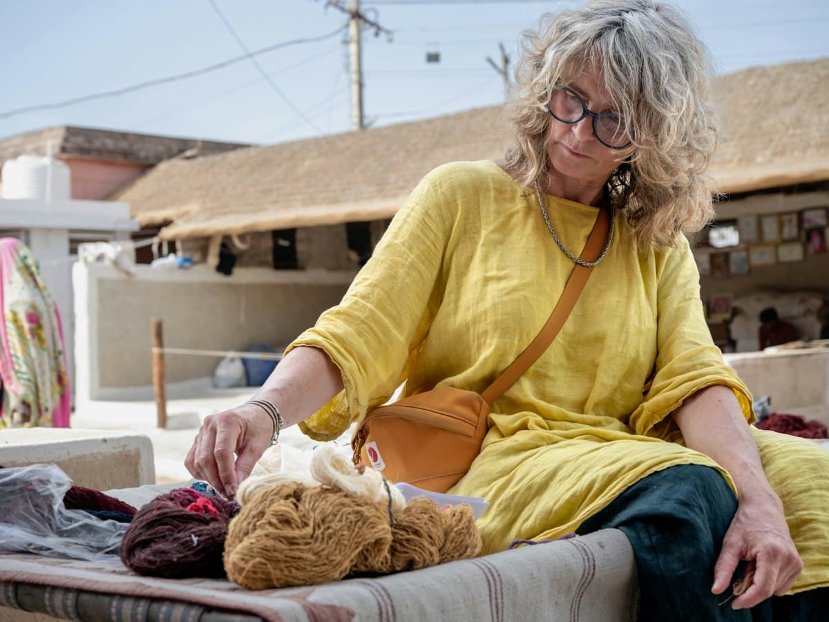 A woman handling skeins of hand-spun wool on a charpoy in Bhujodi, Kutch, Gujarat, in daylight