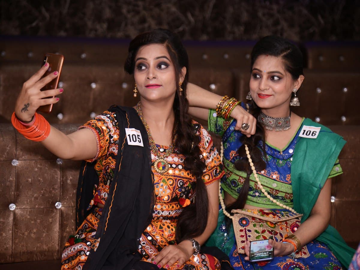 Two women in traditional embroidered Gujarati garba attire at a garba event, India