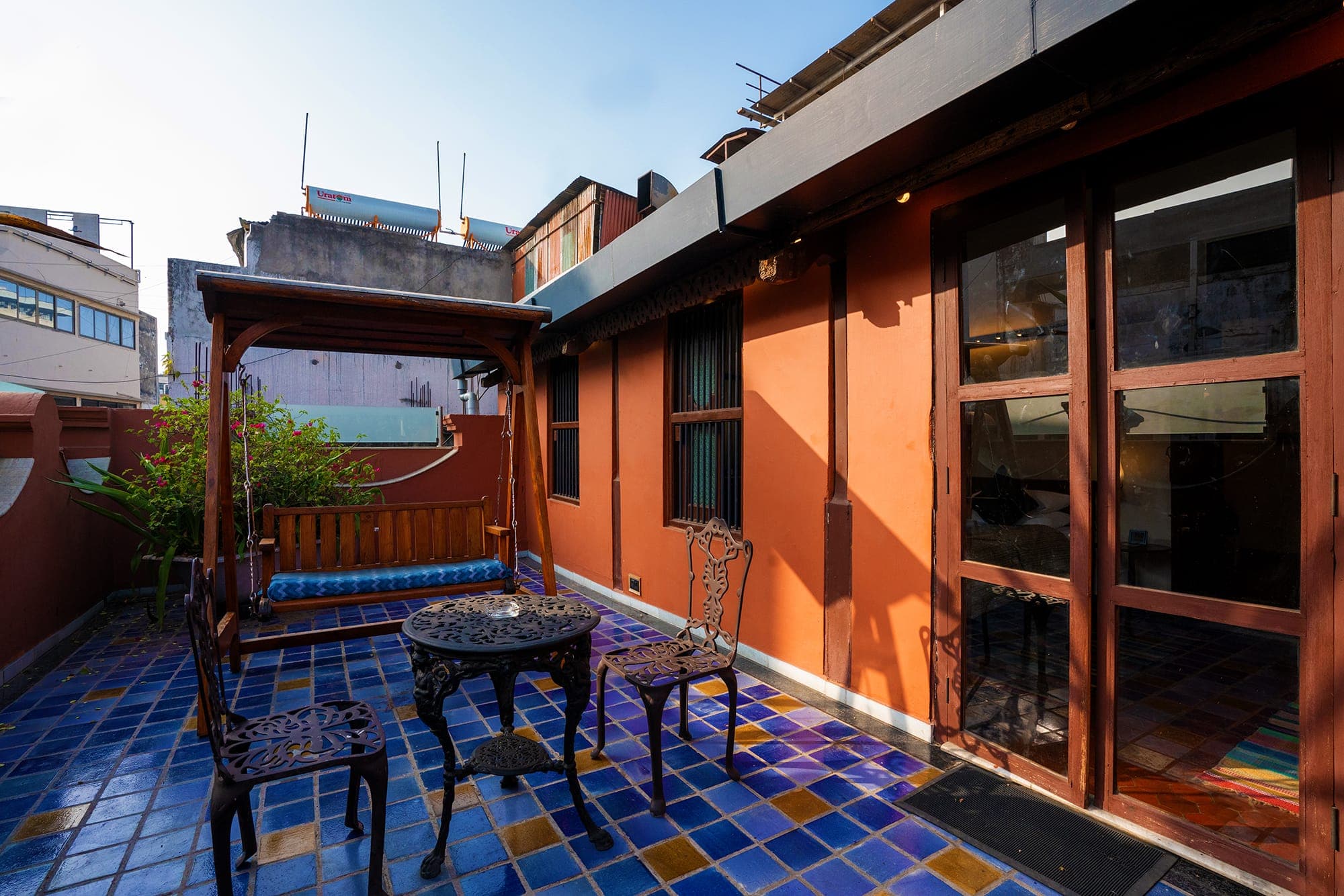 Terrace seating with a Gujarati swing and teak-framed windows at The House of MG, Ahmedabad