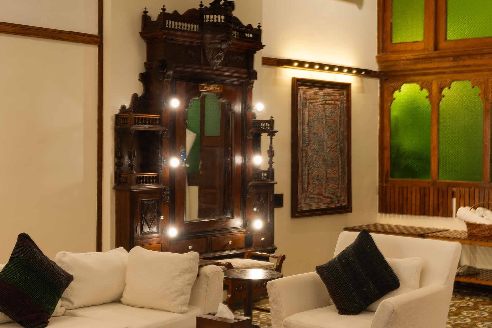 Heritage lounge with a carved wooden cabinet and green stained-glass windows at The House of MG