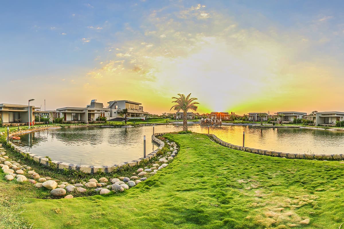 Lake villas and lawns at Araiya Gir glowing at sunset near Sasan Gir