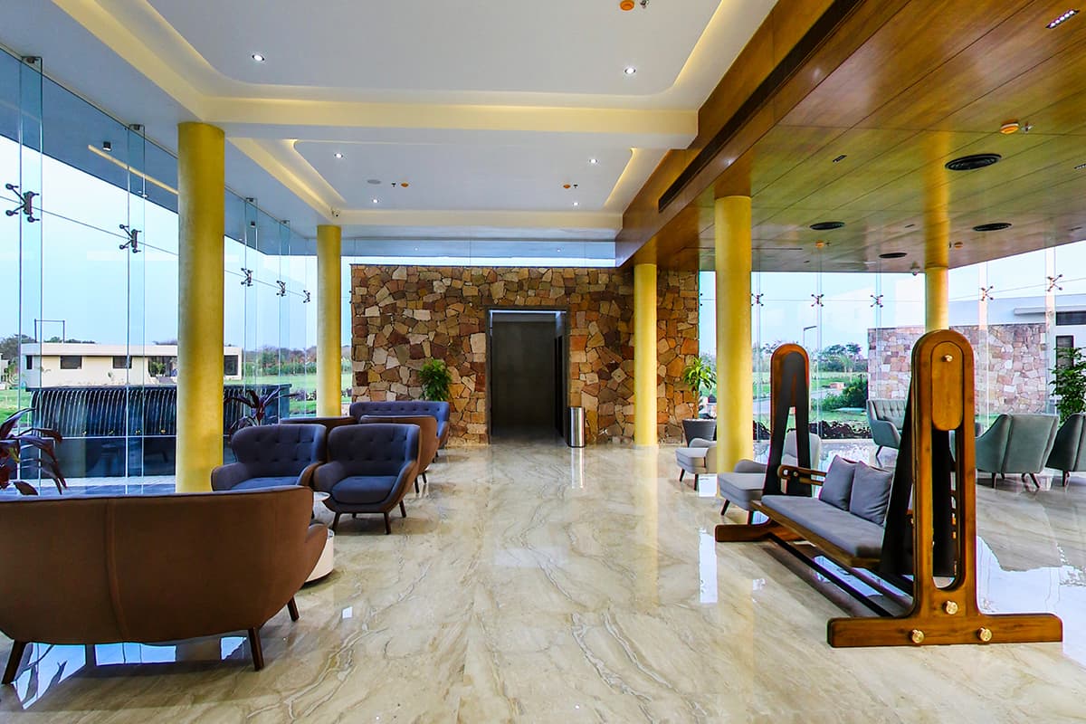 Glass-walled lobby lounge overlooking the fields at Araiya Gir