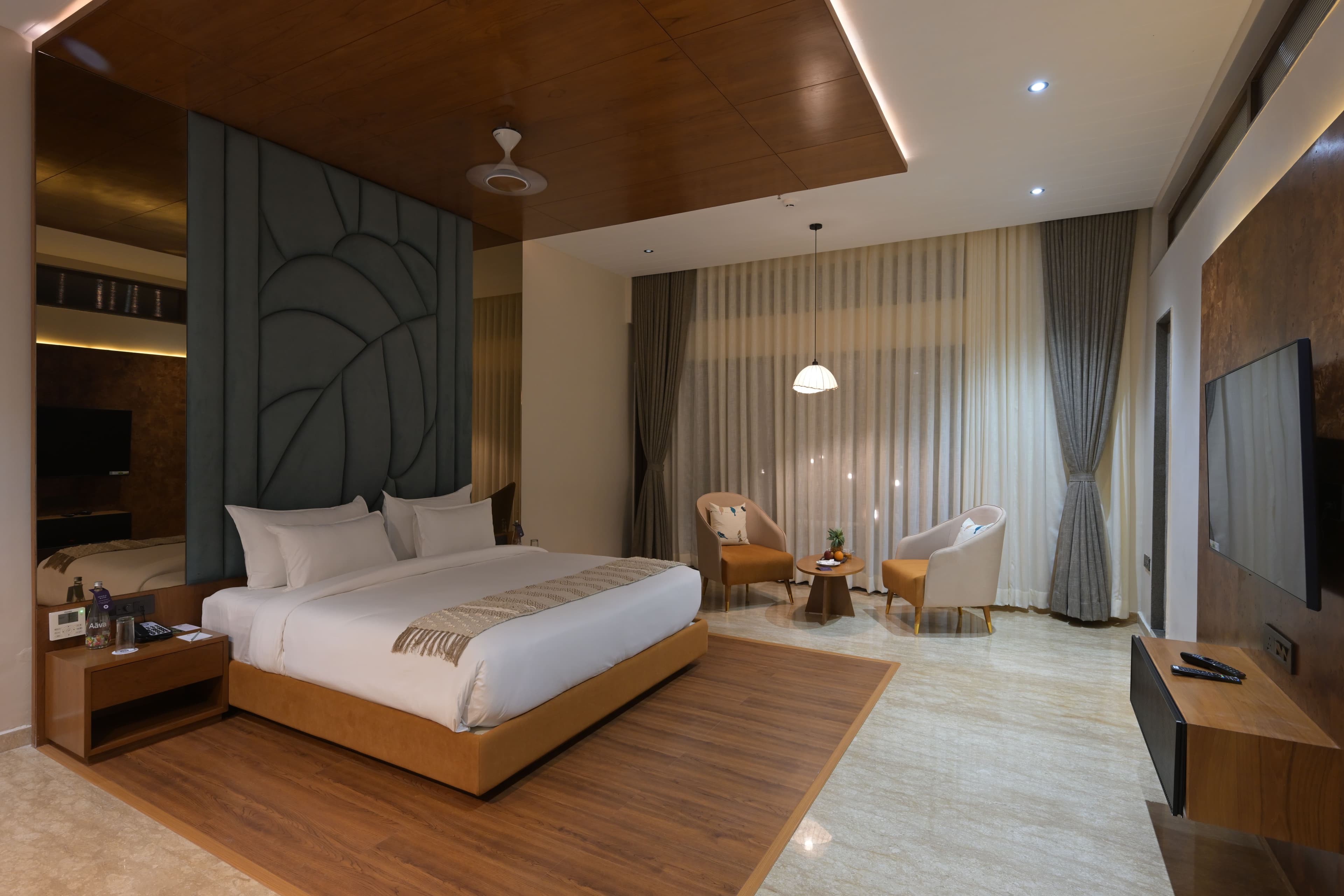 Villa bedroom with a king bed, seating and dark leaf-panelled headboard at Araiya Gir