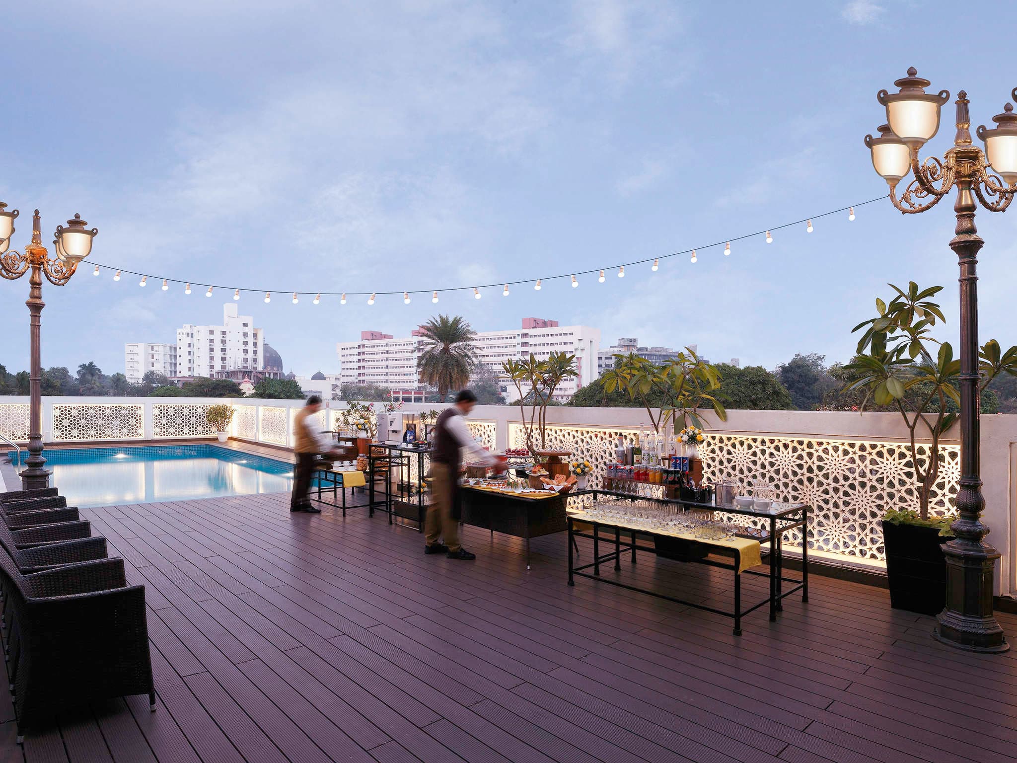 Rooftop pool terrace with lamp posts and city skyline at Grand Mercure Vadodara Surya Palace