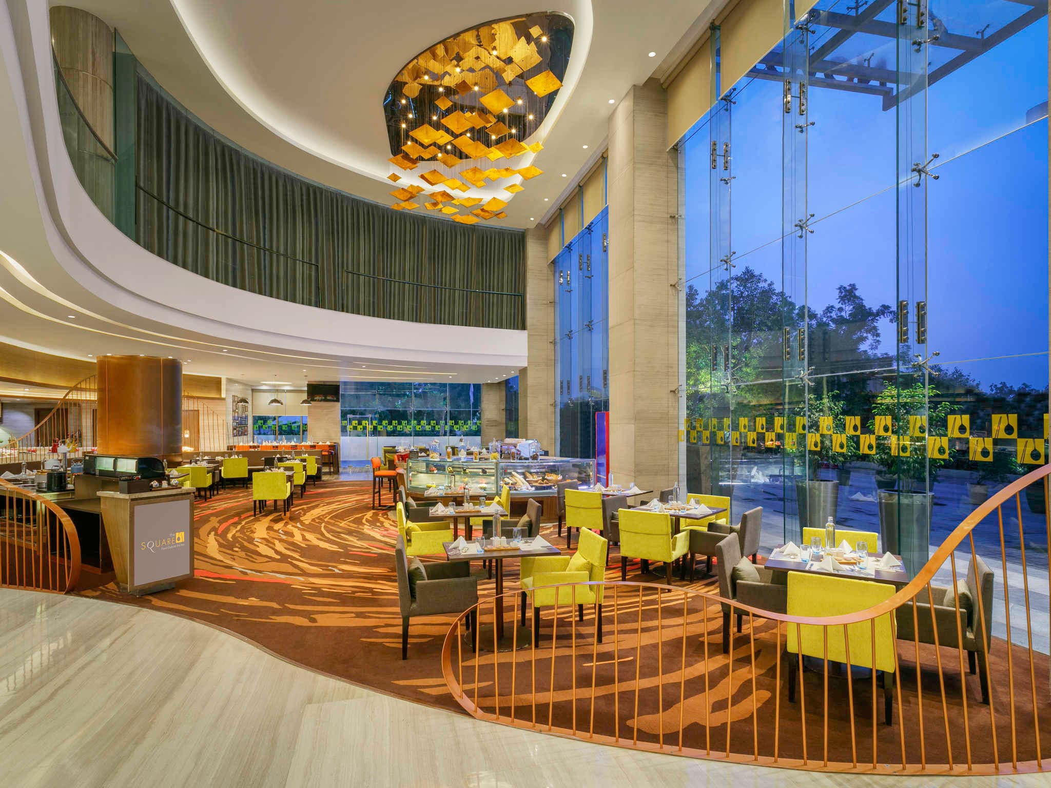 The Square all-day restaurant with glass frontage and pendant chandelier at Novotel Ahmedabad