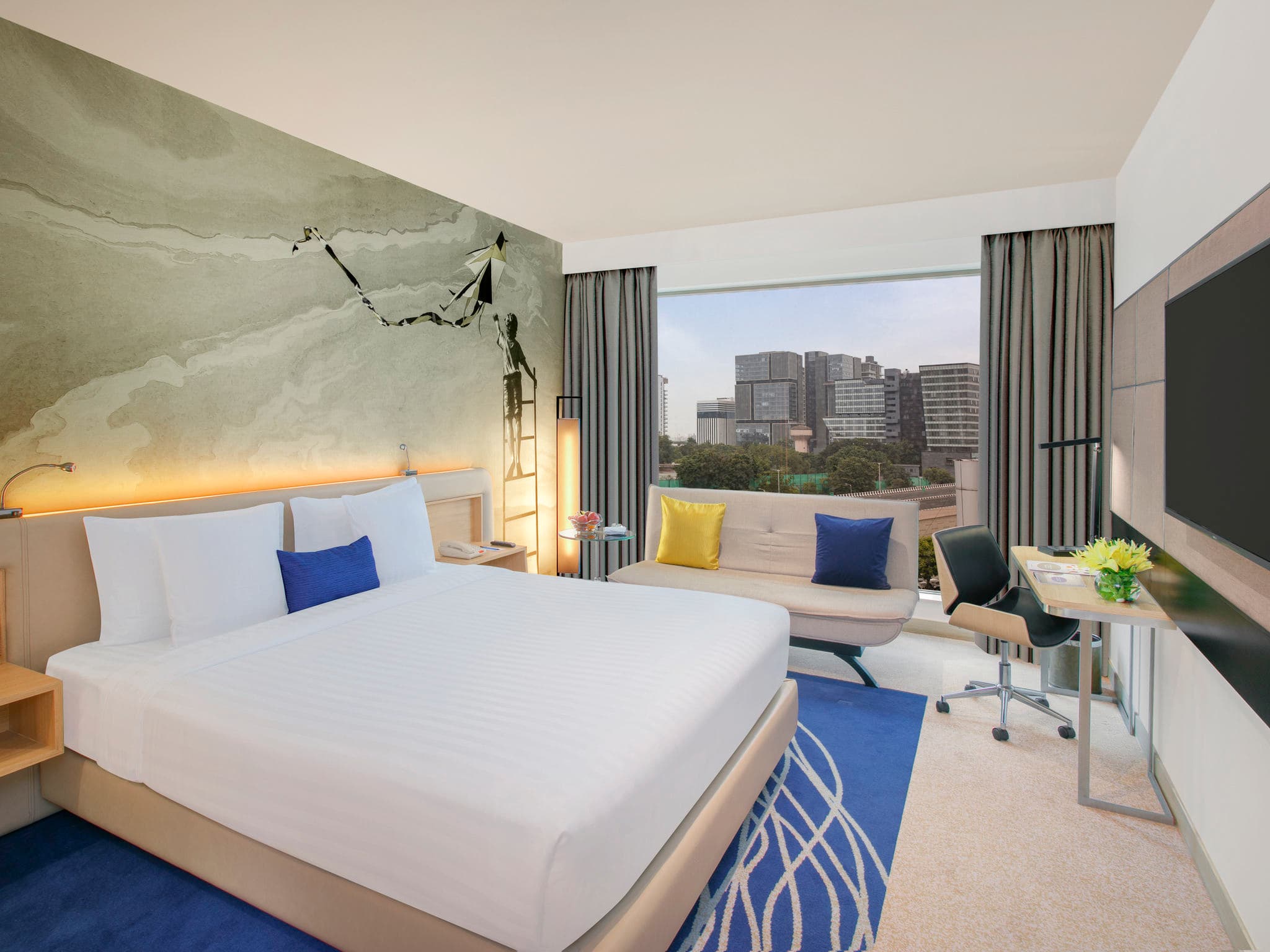 Premier Room with king bed, sofa and blue-and-white decor at Novotel Ahmedabad