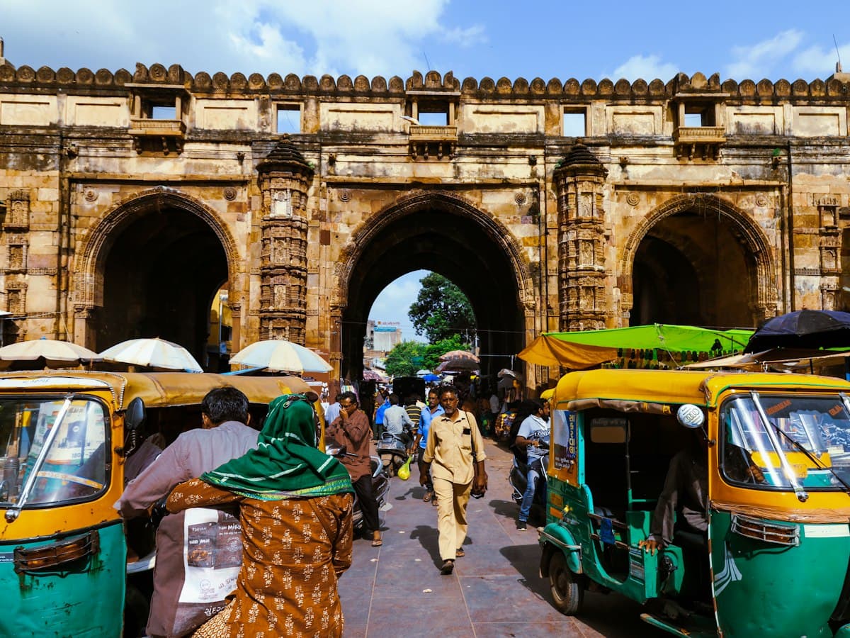 Auto-rickshaws and pedestrians passing beneath the sandstone arches of Teen Darwaza in the old city of Ahmedabad, Gujarat