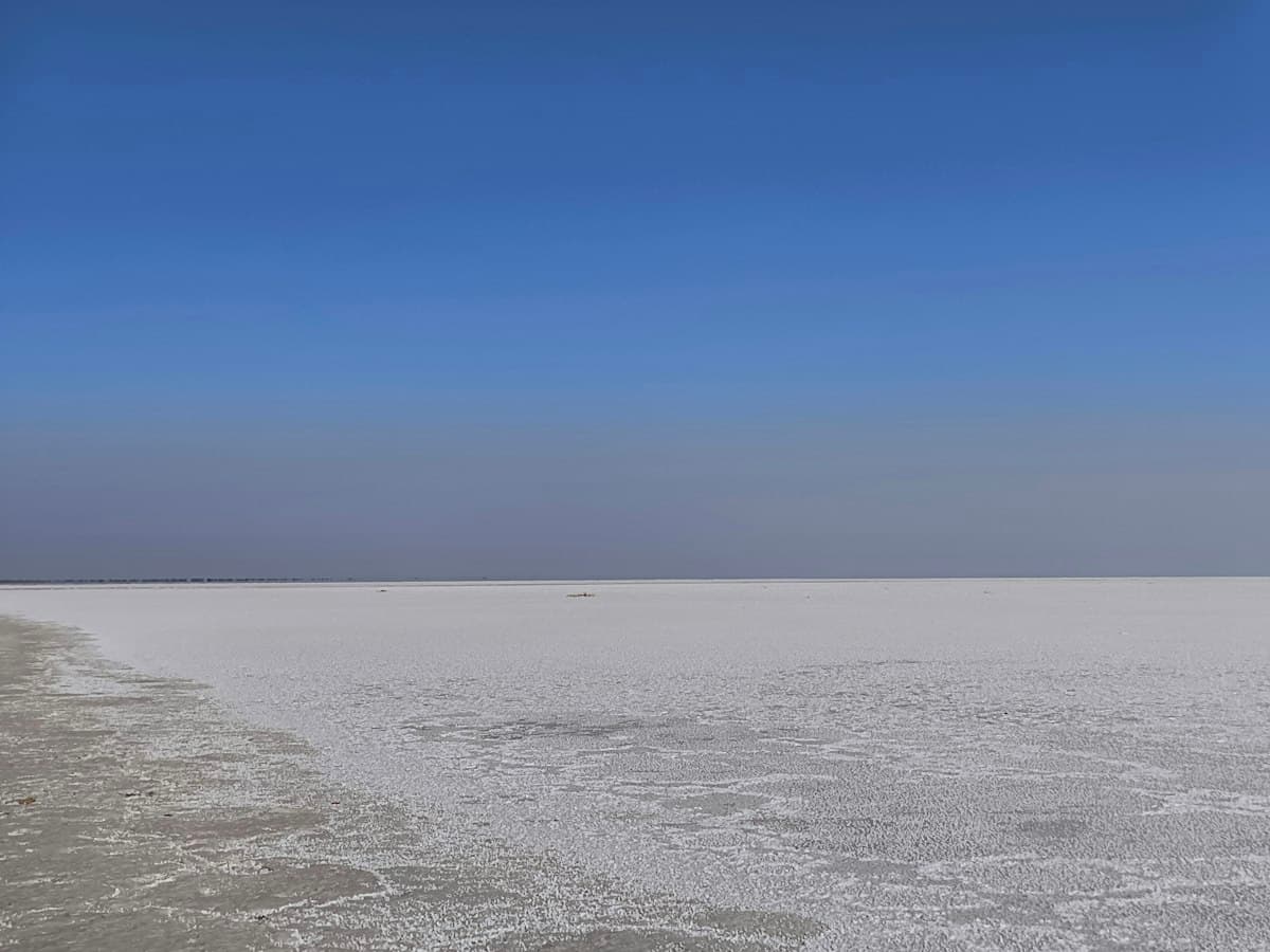 A vast white salt flat under a clear blue sky on the road to Dholavira in the Rann of Kutch, Gujarat