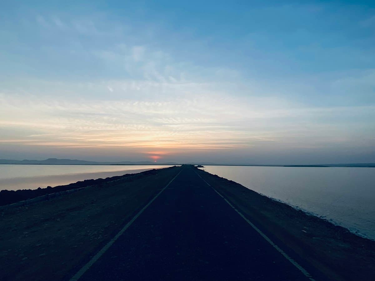 A road running straight across the Rann of Kutch as the sun sets on the horizon, on the Khavda to Dholavira highway, Gujarat
