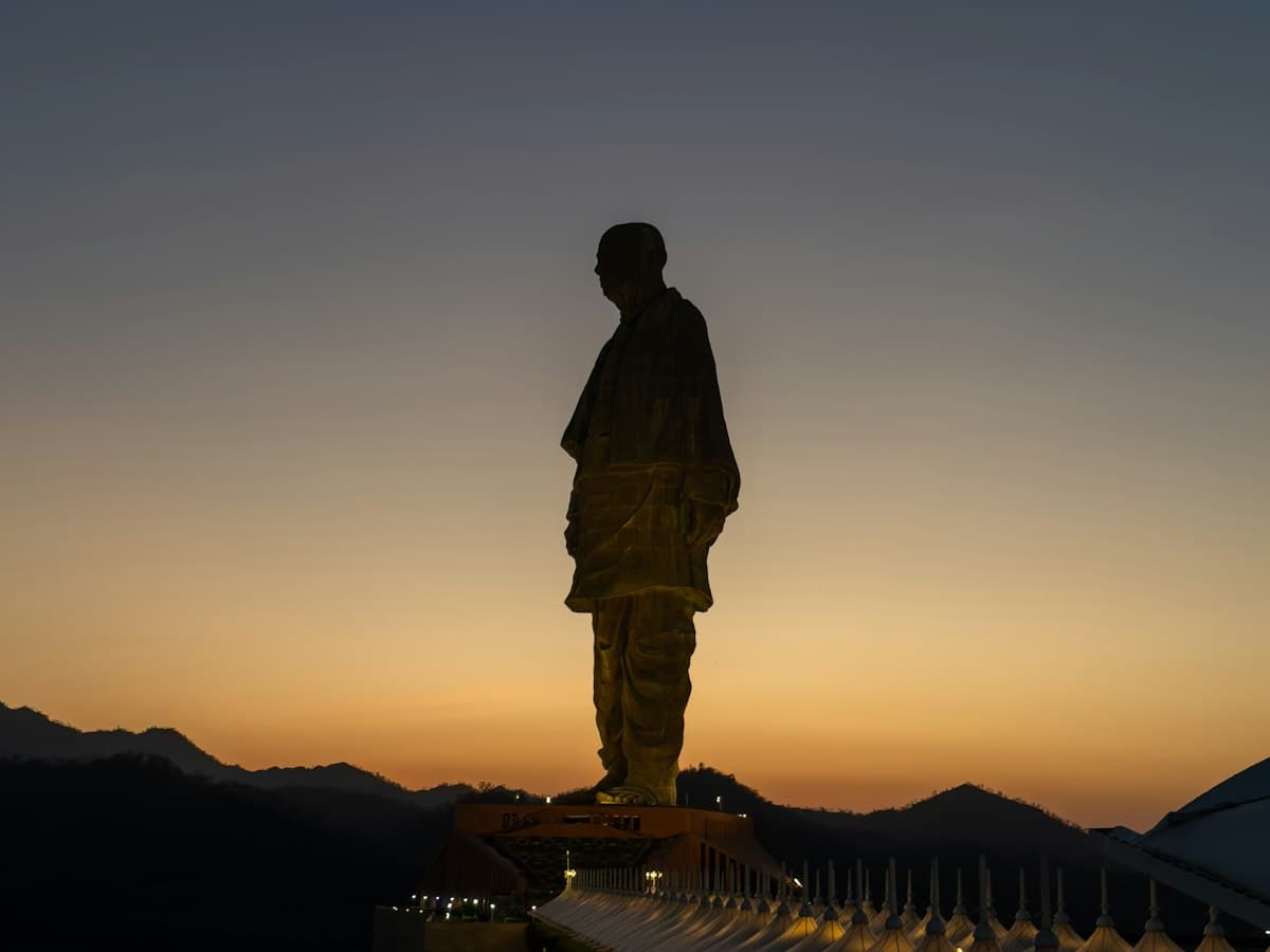 Silhouette of the Statue of Unity against a dusky orange sky at Kevadia, Gujarat