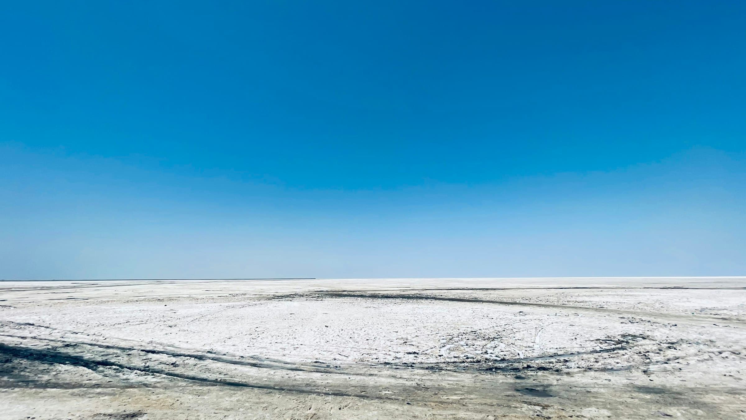 The white salt desert of the Rann of Kutch stretching to the horizon beneath a deep blue sky, Gujarat