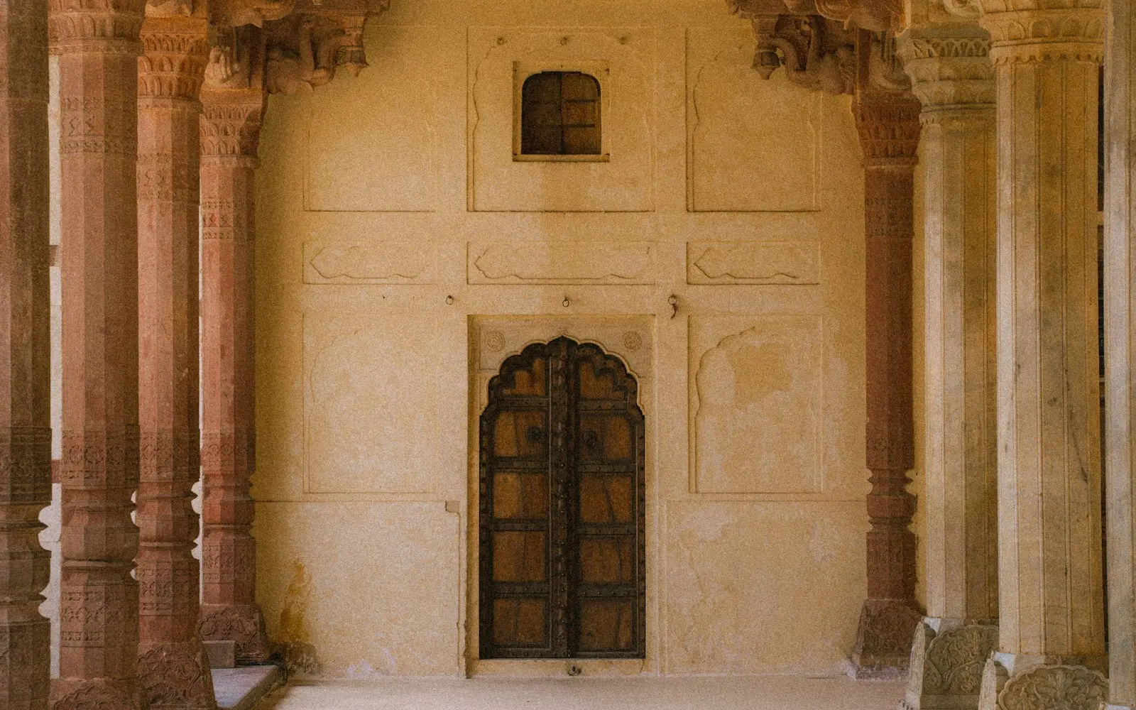 Carved sandstone and marble pillars flanking a wooden door inside Amber Fort