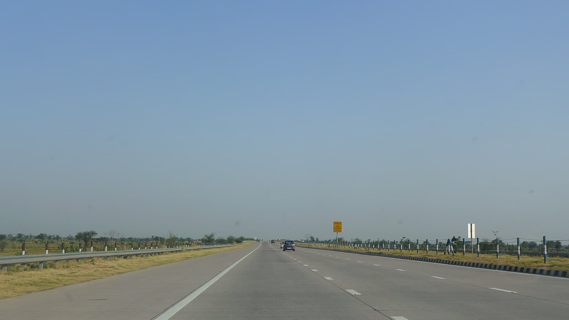 Wide divided Yamuna Expressway running straight across flat farmland