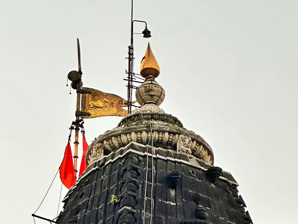 The spire of the Trimbakeshwar temple hung with flags against a pale sky, near Nashik, Maharashtra